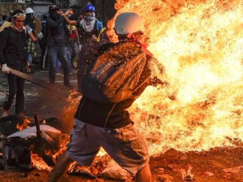 Un manifestante prende fuoco, dopo l'esplosione del serbatoio di una moto della polizia, durante gli scontri in una protesta contro il presidente venezuelano Nicolas Maduro, a Caracas (LaPresse)