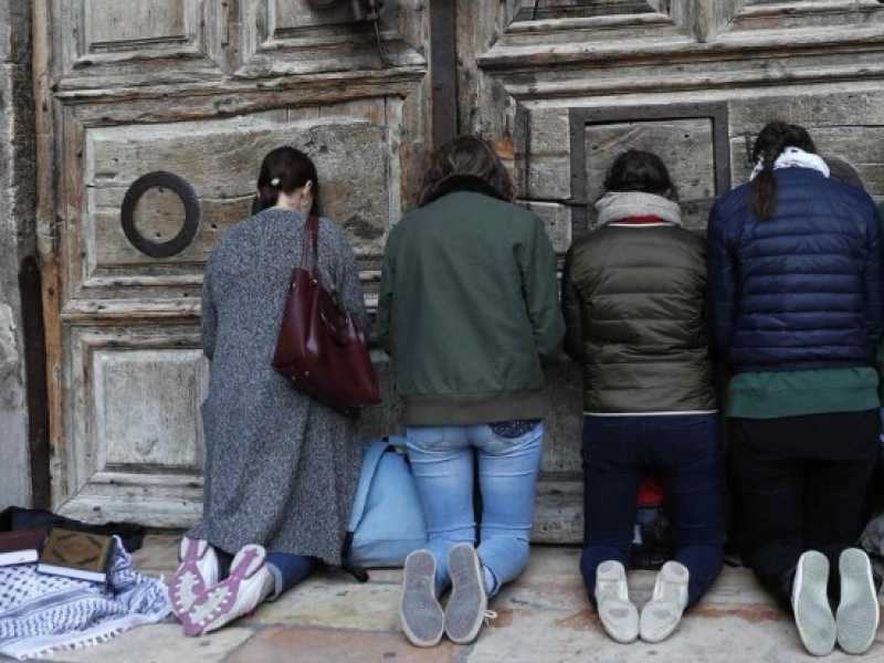 Fedeli pregano davanti all'ingresso del Santo Sepolcro chiuso per protesta contro  il governo israeliano e il sindaco di Gerusalemme (foto LaPresse)