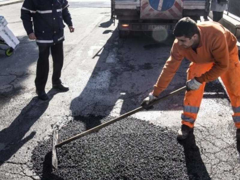 Operai al lavoro a Roma per riparare buche stradali (foto LaPresse)