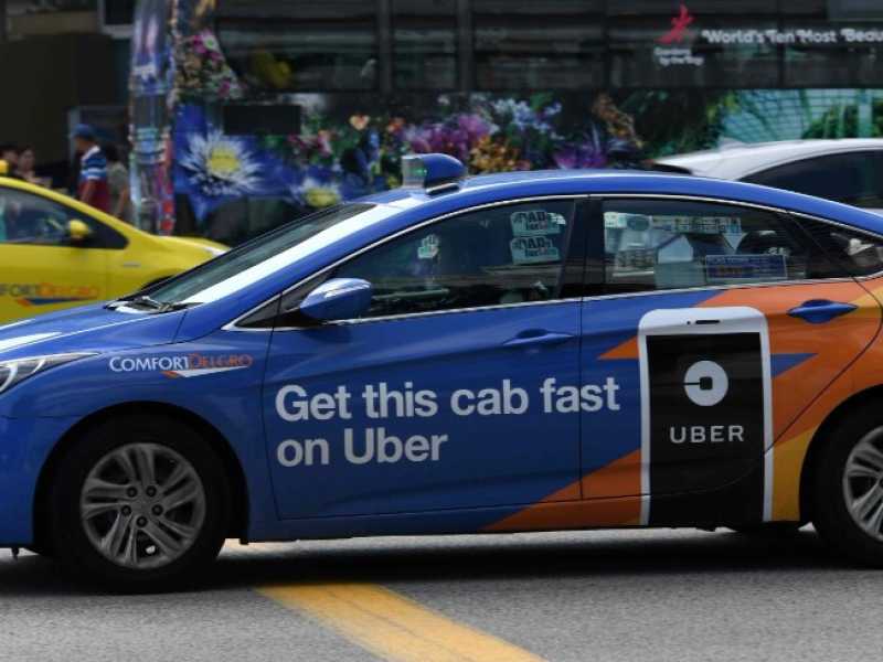 Un taxi Comfort Delgro con annunci pubblicitari su Uber attraversa la strada a Singapore (foto LaPresse)