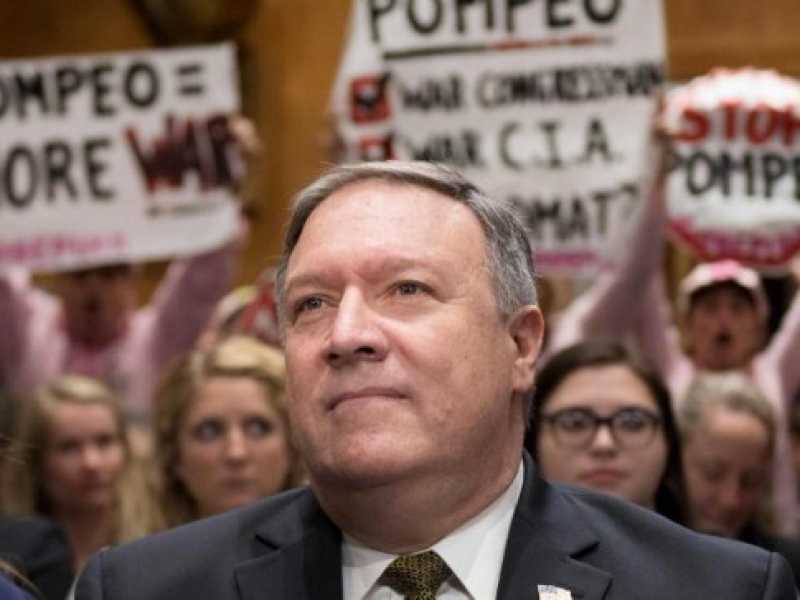 Alcuni manifestanti mostrano cartelli di protesta alle spalle di Mike Pompeo durante la sua audizione a Capitol Hill per essere confermato nuovo segretario di stato (foto LaPresse)