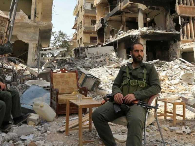 Tre soldati dell'esercito siriano tra le macerie di Ghouta (foto LaPresse)