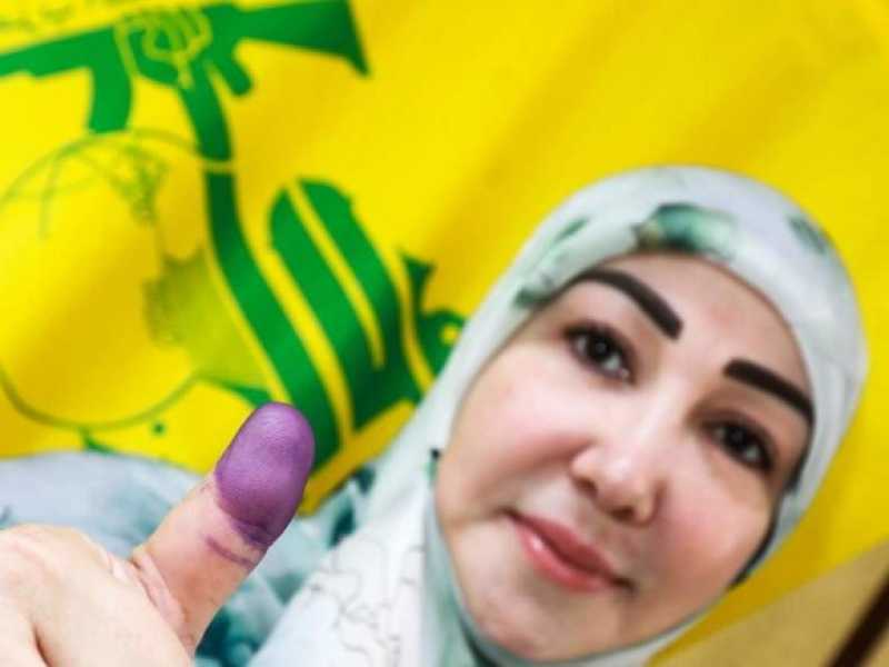 Un'elettrice libanese e sullo sfondo una bandiera di Hezbollah (foto LaPresse)