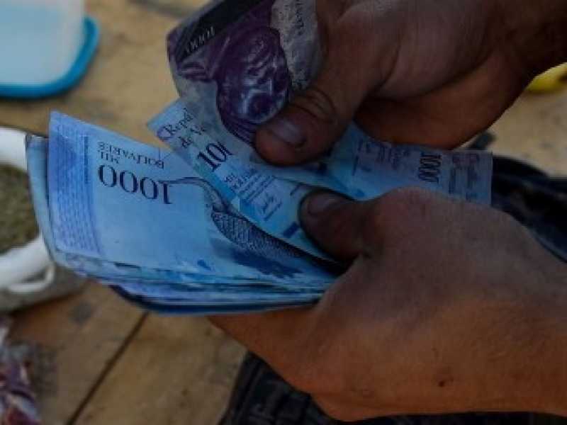 Il 20 giugno 2018. Un uomo conta 1000 banconote Bolivar per comprare generi alimentari nel mercato municipale di Coche, un quartiere di Caracas (foto LaPresse)