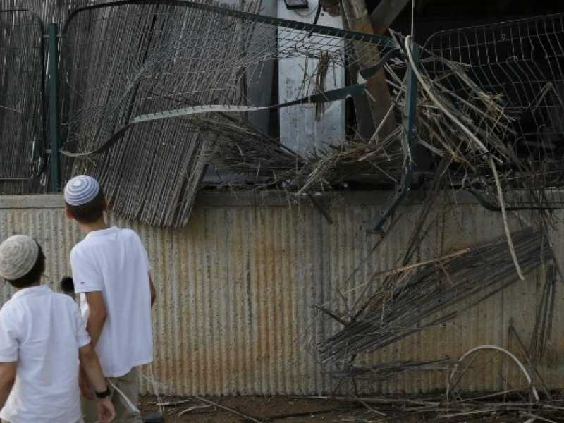 Giovani residenti di Sderot, nel sud dell'Israele, camminano di fronte a una recinzione danneggiata da un razzo lanciato dalla Striscia di Gaza il 14 luglio 2018 (foto LaPresse)