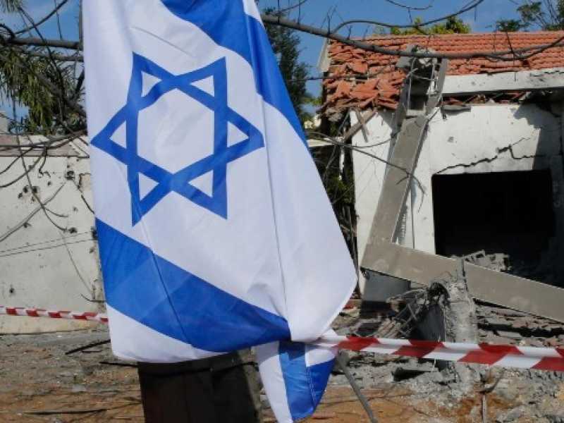 Israeliani alzano la bandiera nazionale mentre ispezionano il danno in una casa causato dai razzi sparati dalla Striscia di Gaza, nella citt&agrave; di Ashkelon, il 13 novembre 2018 (foto LaPresse)