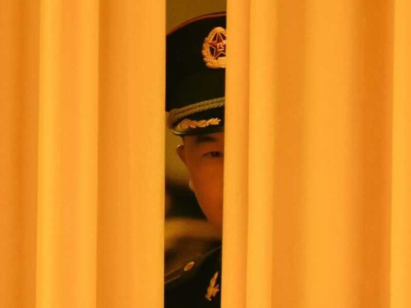 Una guardia presidenziale guarda attraverso la tenda della Grande Sala del Popolo di Pechino (foto LaPresse)