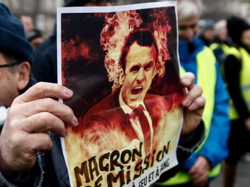 Un manifestante a Parigi espone un cartello: "Macron dimettiti" (Foto LaPresse)