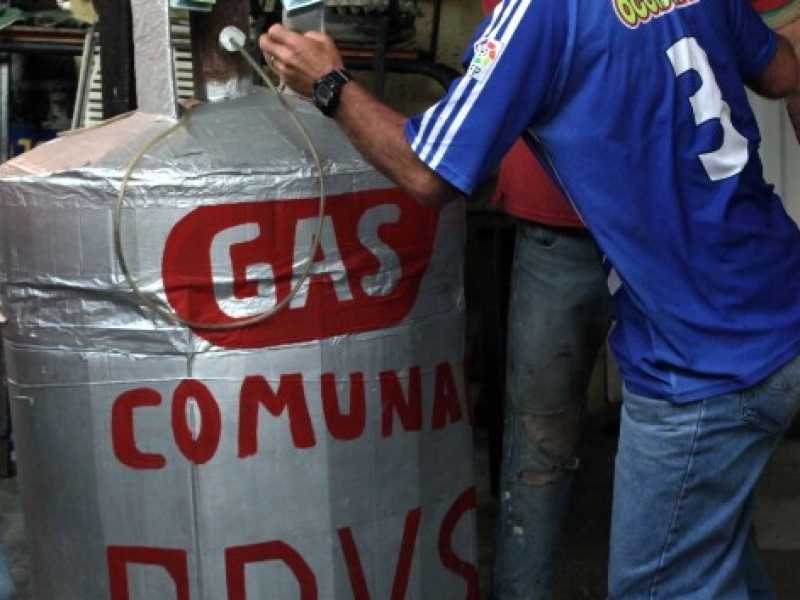 Un venezuelano posa alcune banconote su una tanica di benzina (Foto LaPresse)