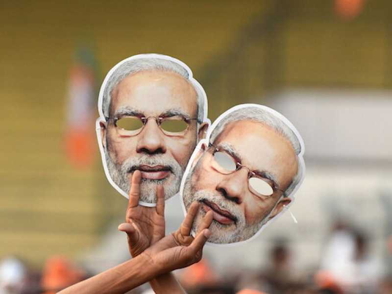 Un sostenitore del Bjp sveltola le foto di Narendra Modi (Foto LaPresse)
