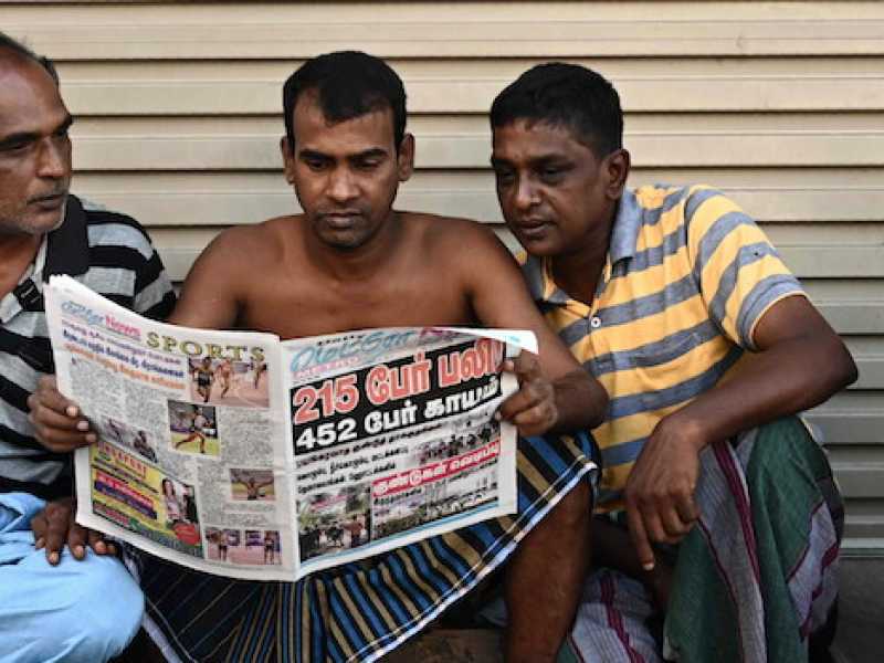 Alcuni cingalesi leggono il giornale dopo gli attacchi terroristici di domenica (Foto LaPresse)