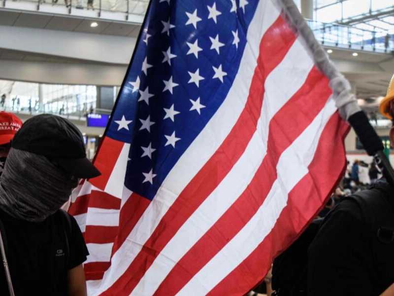 A Hong Kong un manifestante anti cinese mostra la bandiera americana (foto LaPresse)