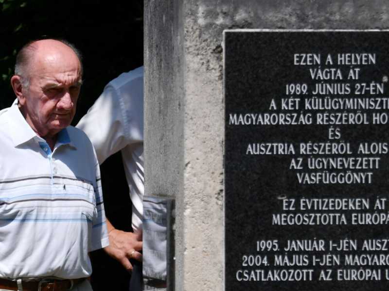 Un uomo guarda una lapide commemorativa della rimozione della barriera che rappresentava la Cortina di ferro (LaPresse)