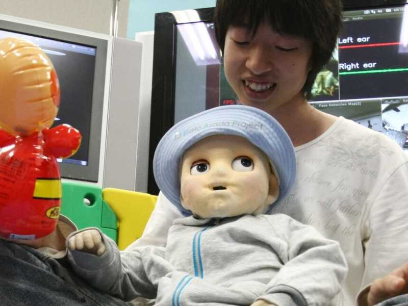 Uno studente giapponese gioca con un bambino robot in un laboratorio dell'Universit&agrave; di Tokyo (foto LaPresse)