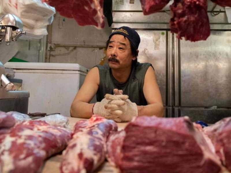 Un macellaio in attesa di clienti alla sua bancarella in un mercato di Pechino (foto LaPresse)