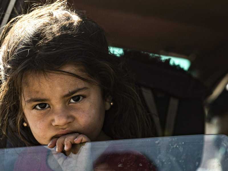 Una bambina siriana abbandona con la famiglia la zona a nord di Ras al-Ain, al confine con la Turchia (foto LaPresse)