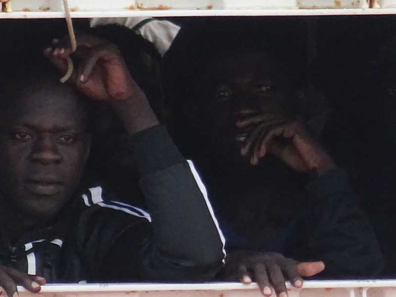 Due migranti affacciati dall'obl&ograve; della nave umanitaria Ocean Viking (foto LaPresse)