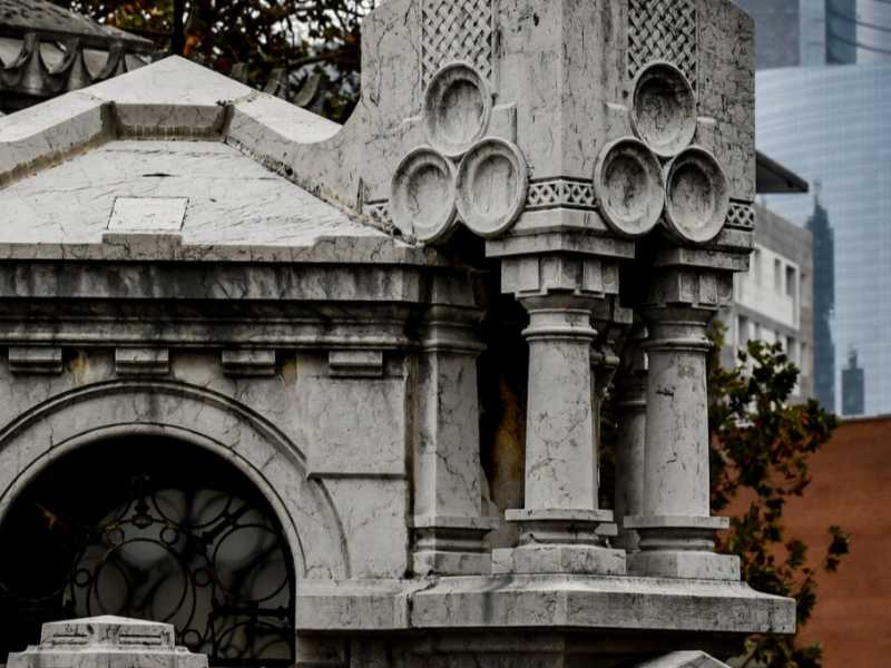 Una tomba del cimitero Monumentale di Milano. Alle spalle la Torre Unicredit (foto LaPresse)