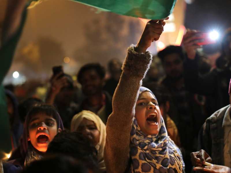 Ragazze sventolano la bandiera indiana a Shaheen Bagh (foto AP/Altaf Qadri via LaPresse)