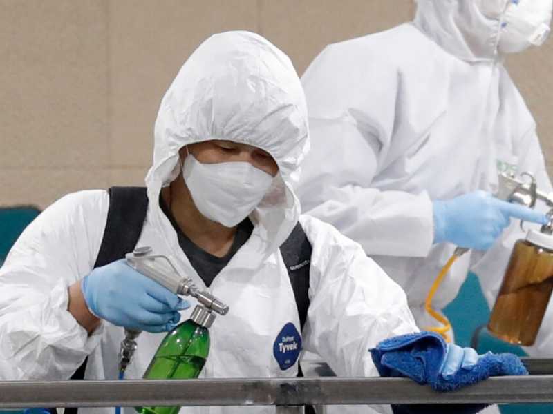 Operatori sanitari disinfettano un'aula all'interno di un liceo di Seul (foto LaPresse)