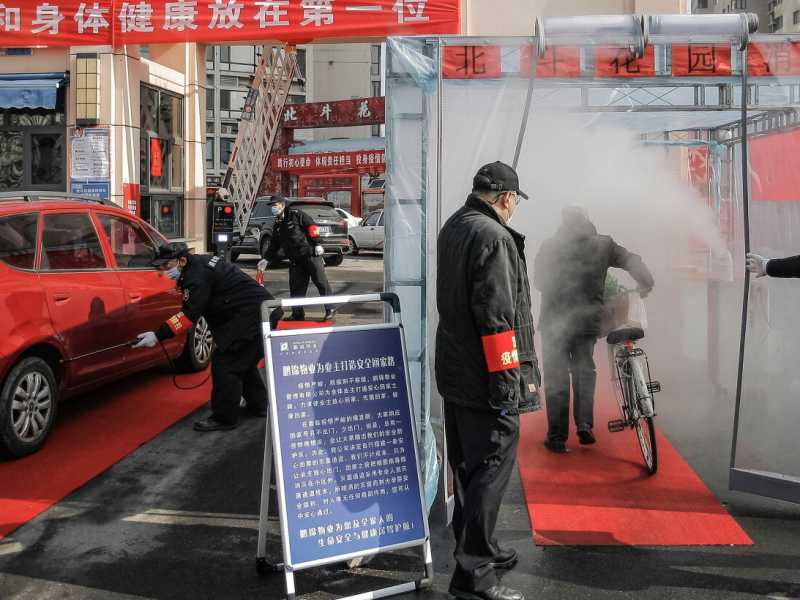 Un ciclista passa attraverso una pioggia di spray disinfettante prima di tornare a casa, in un complesso residenziale nel comune di Tianjin nel nord della Cina (Chinat