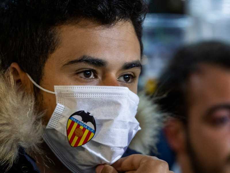 Un tifoso del Valencia con mascherina “brandizzata” guarda in televisione la gara di Champions League, a porte chiuse, tra la sua squadra e l'Atalanta (foto LaPresse)