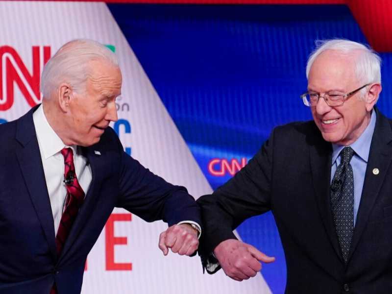 I due candidati dem, Biden (a sinistra) e Sanders, si sono salutati con un colpo di gomito, invece di darsi la mano (LaPresse)