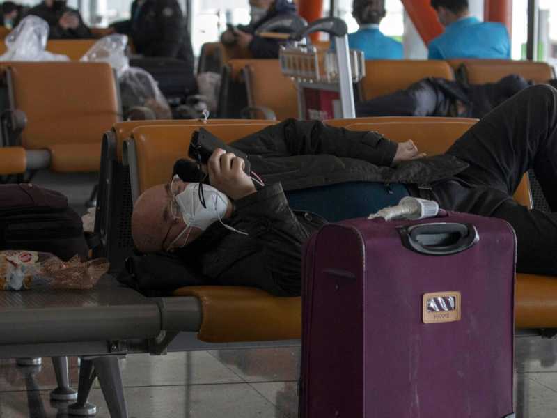 Un passeggero attende il suo volo all'aeroporto di Pechino (foto LaPresse)
