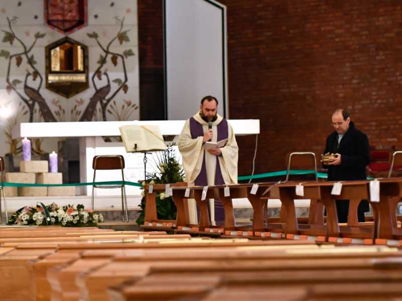 Un prete benedice delle salme nella chiesa di Seriate (foto LaPresse)