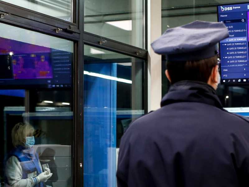 Una guardia di sicurezza controlla l&rsquo;ingresso di operai in una fabbrica tramite termoscanner (foto LaPresse)