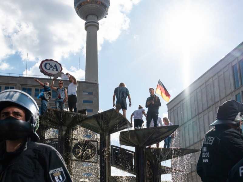 La gente sale sulla fontana "Fontana dell'amicizia tra le nazioni" durante una manifestazione non autorizzata ad Alexanderplatz a Berlino,