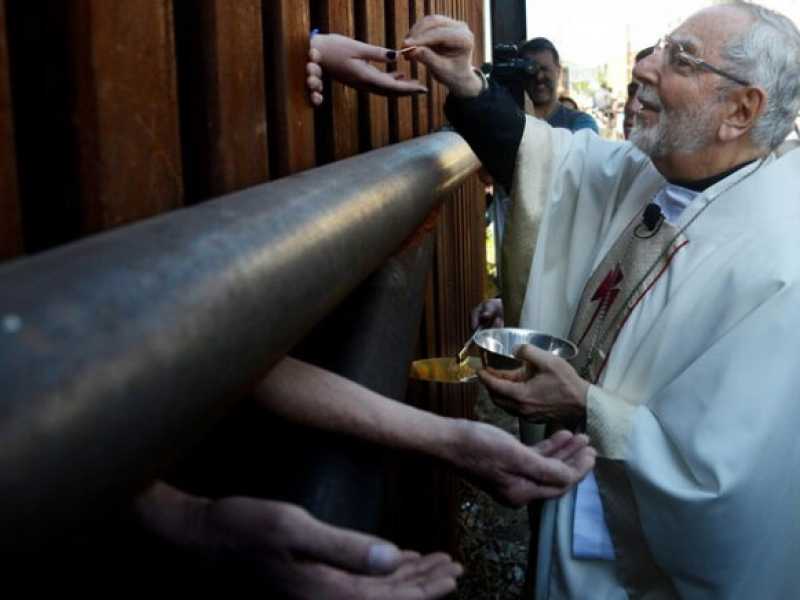 Mons. Gerald Kicanas, mentre d&agrave; la comunione al muro che separa Arizona e Messico