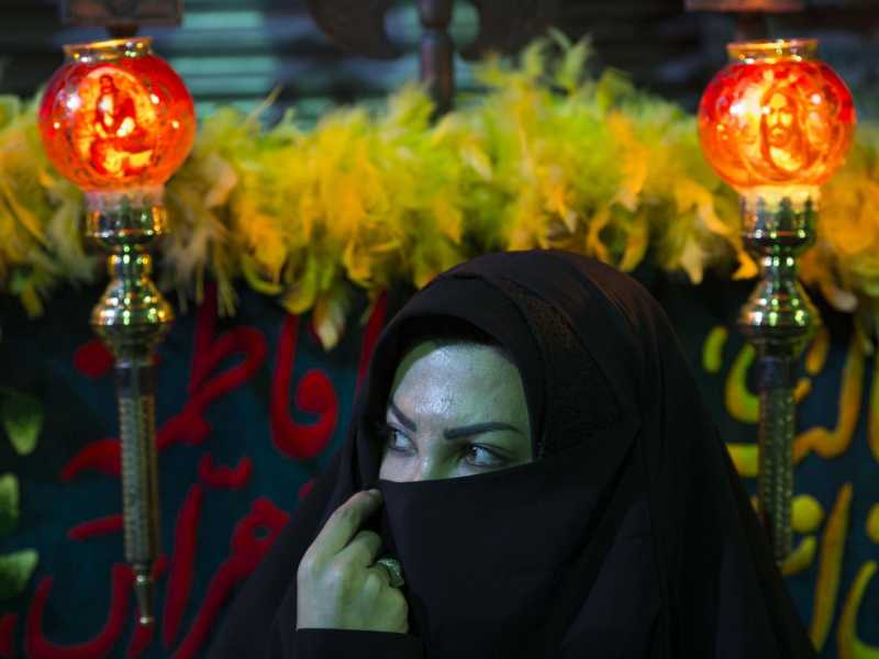 Una donna velata si guarda intorno seduta a un bazaar di Teheran durante le celebrazioni della 'Tasoua' (LaPresse)