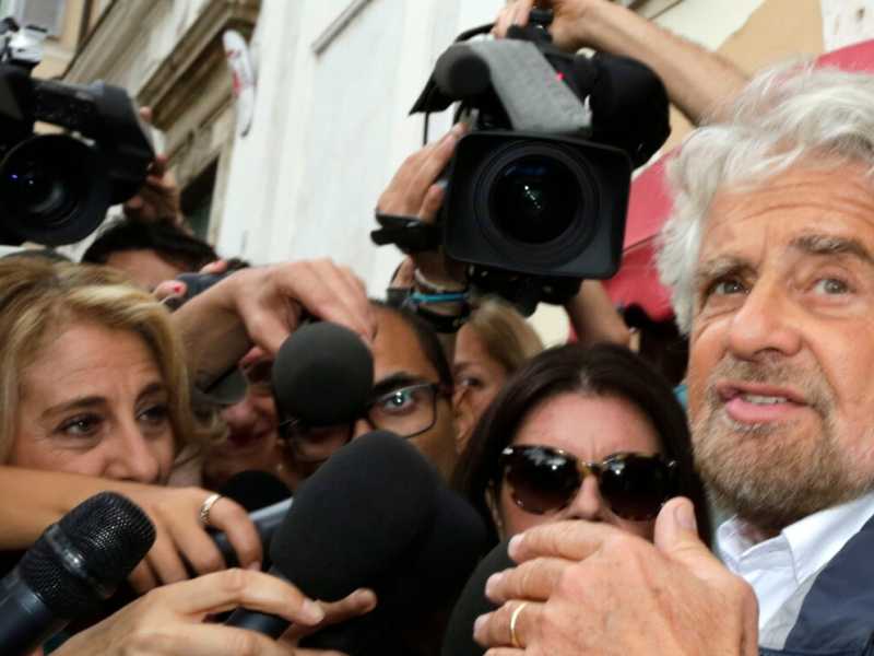 Beppe Grillo all'Hotel Forum circondato dai giornalisti (foto LaPresse)