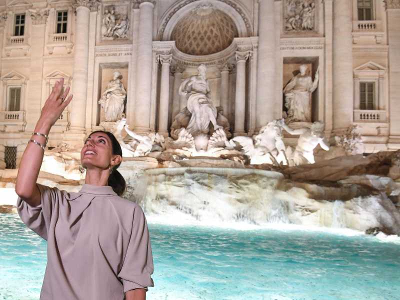 La sindaca di Roma Virginia Raggi mentre lancia una monetina dentro alla fontana di Trevi (foto Ansa)&nbsp;<br />