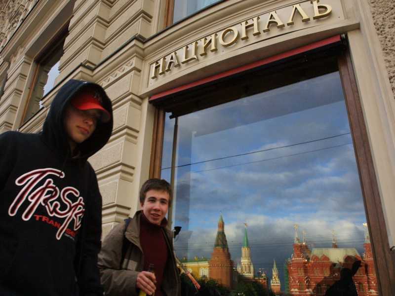 Adolescenti passano davanti all'Hotel National a Mosca. La vetrina riflette il Cremlino (Oleg Nikishin / Getty Images)&nbsp;<br />