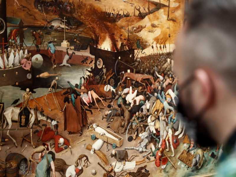 Un visitatore guarda "Il Trionfo della Morte" di Pieter Bruguel il Vecchio (olio su tavola, conservato al Museo del Prado di Madrid. Foto Ansa)