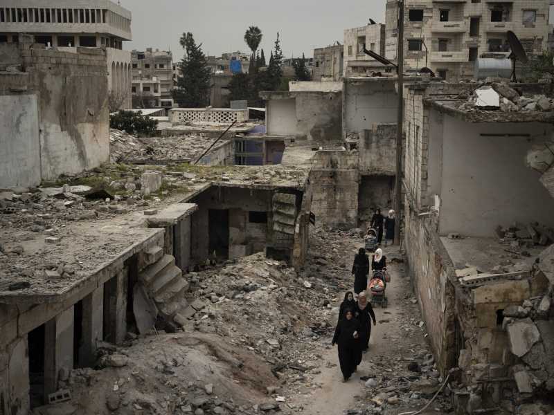 In questa foto del 12 marzo 2020, alcune donne camminano in un quartiere gravemente danneggiato dagli attacchi aerei a Idlib, in Siria (AP Photo / Felipe Dana, File)&nbsp;<br />