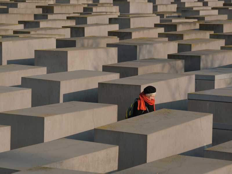 BERLIN, GERMANY - JANUARY 24: An elderly visitor walks among stellae at the Memorial to the Murdered Jews of Europe <br />