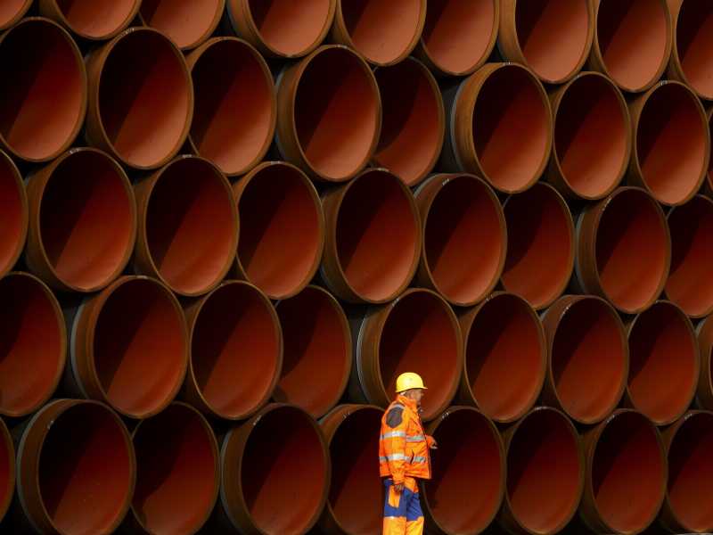 Un lavoratore davanti a tubi accatastati nel cantiere del Nord Stream 2 sull'isola di Ruegen, Germania (foto di Carsten Koall/Getty Images) <br />