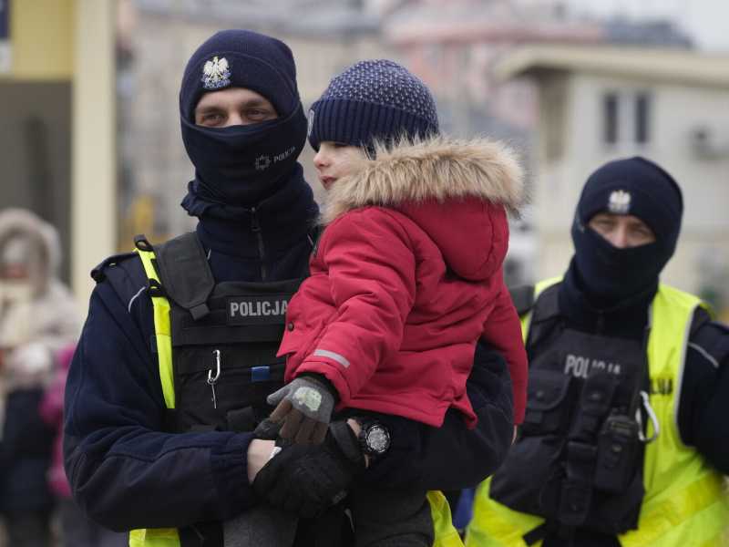 Un ufficiale di polizia con un bambino che arriva in Polonia su un treno da Odesa, in Ucraina (Foto AP/Czarek Sokolowski) <br />