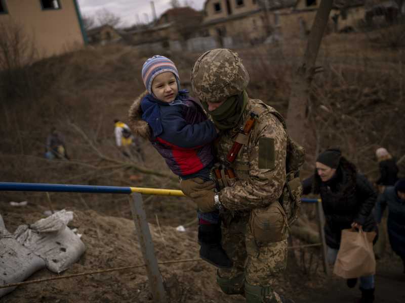 I soldati ucraini aiutano le famiglie famiglia in fuga dopo aver attraversato il fiume Irpin, a Kyiv (foto LaPresse) <br />