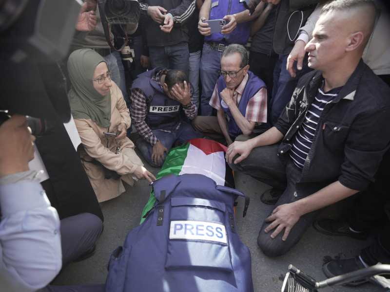 I colleghi circondano il corpo di Shireen Abu Akleh, giornalista di Al Jazeera (Foto AP/Majdi Mohammed)&nbsp;<br />