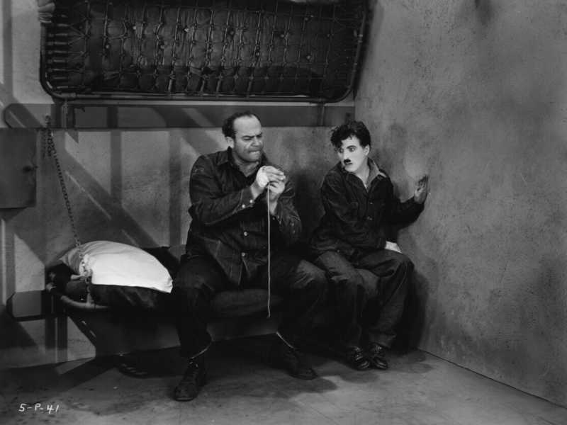 Chaplin in cella con un personaggio dall'aspetto duro in una scena di "Tempi moderni" (Foto di Max Munn Autrey/Hulton Archive/Getty Images) <br />