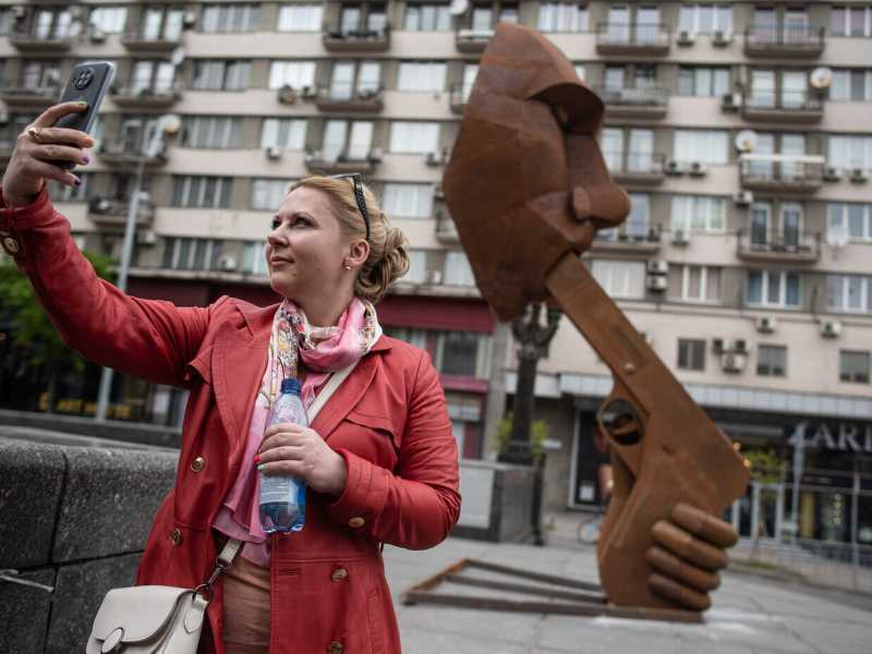 Kyiv, una donna si fa un selfie accanto a una scultura dedicata a Putin, chiamata "Spara a te stesso!" (Alexey Furman/Getty Images) <br />
