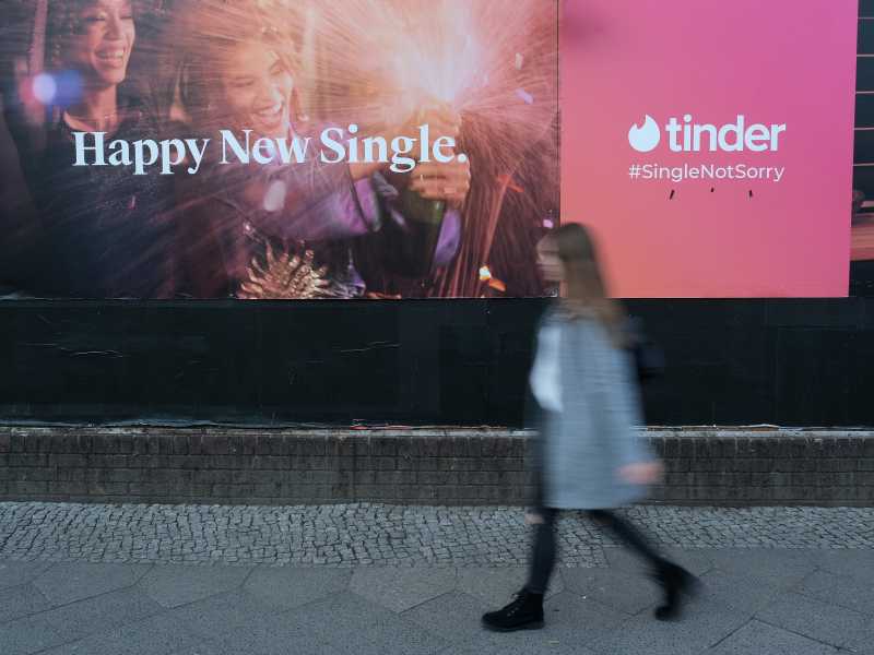 Una donna passa vicino a una pubblicità di Tinder a Berlino, Germania (Getty Images)