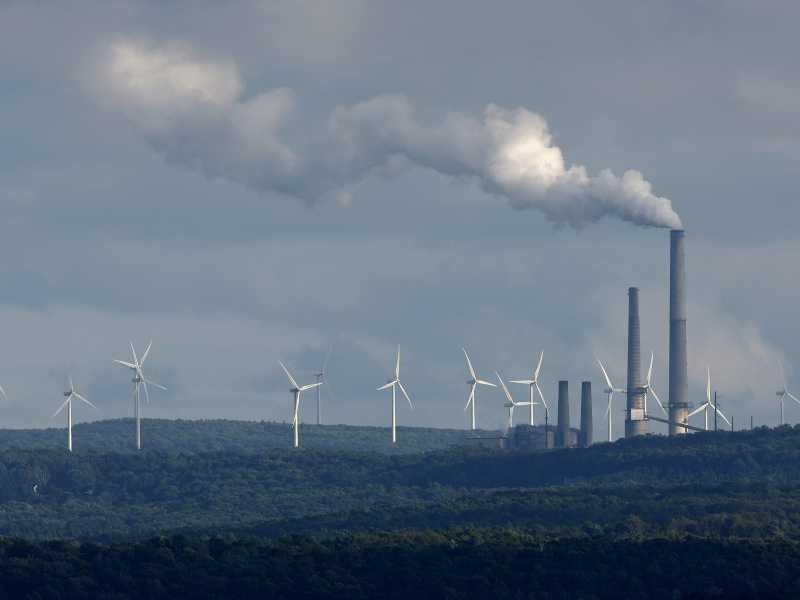  Delle pale eoliche vicino a una ciminiera (Getty Images)
