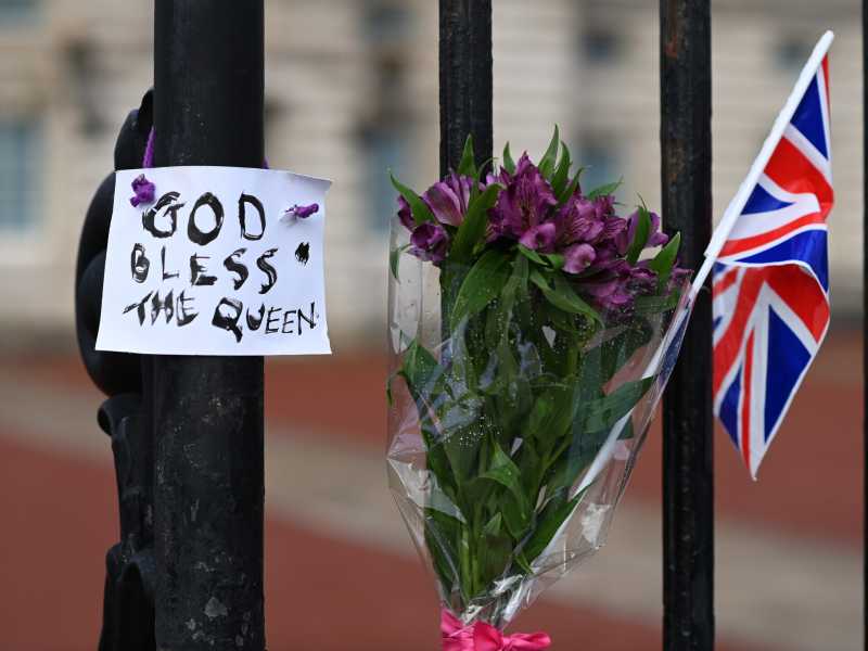 Un mazzo di fiori e un cartello appesi all'esterno di Buckingham Palace (Getty Images)