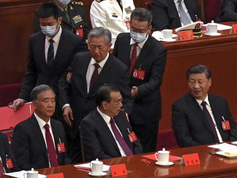 Gli inservienti chiamati dal presidente Xi Jinping portano fuori dalla sala del Congresso del Partito comunista l&rsquo;ex presidente Hu Jintao (LaPresse)&nbsp;<br />
