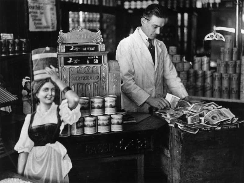 Un negoziante usa una cassa da t&egrave; per conservare denaro che non entra nel registratore di cassa durante l'alta inflazione tedesca (Hulton Archive/Getty Images)&nbsp;<br />